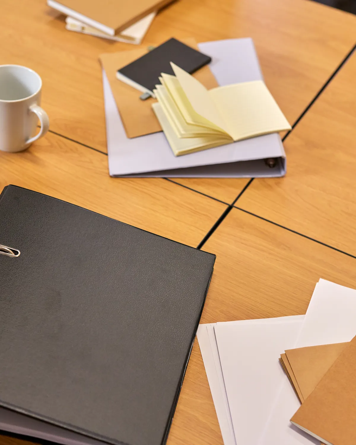 Carpeta de tapa dura y documentación apoyadas sobre una mesa de trabajo